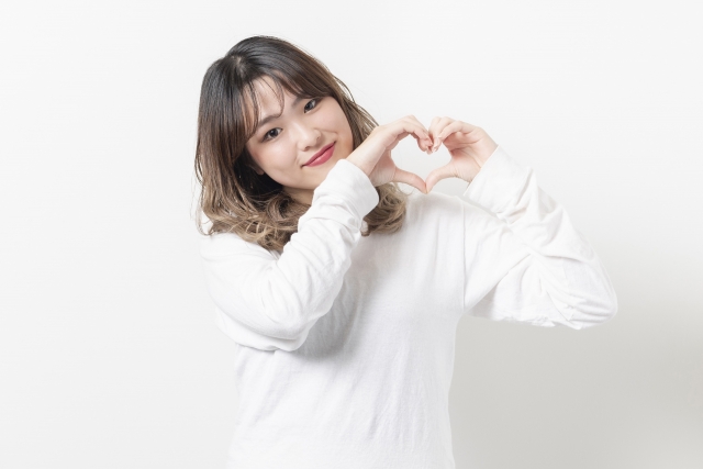 情けは人の為ならず、人に対して情を与えることは回りまわって自分にかえってくる、このことを表すために情勢が自分の両手で💗マークを作り「情」の大切さを訴えている写真。