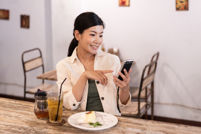 40代の婚活は結婚相談所で！のテーマに合わせ40歳代の女性が食事をしながらスマホでお相手検索をしている写真。気楽にお相手探しができます。